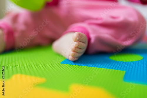 Close up of baby bare feet sitting on colorful puzzle play mat.