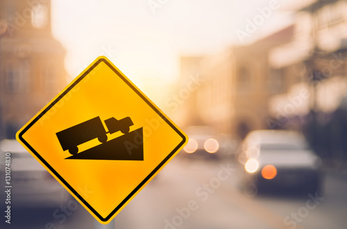 Up hill warning sign on blur traffic road with colorful bokeh light abstract background.