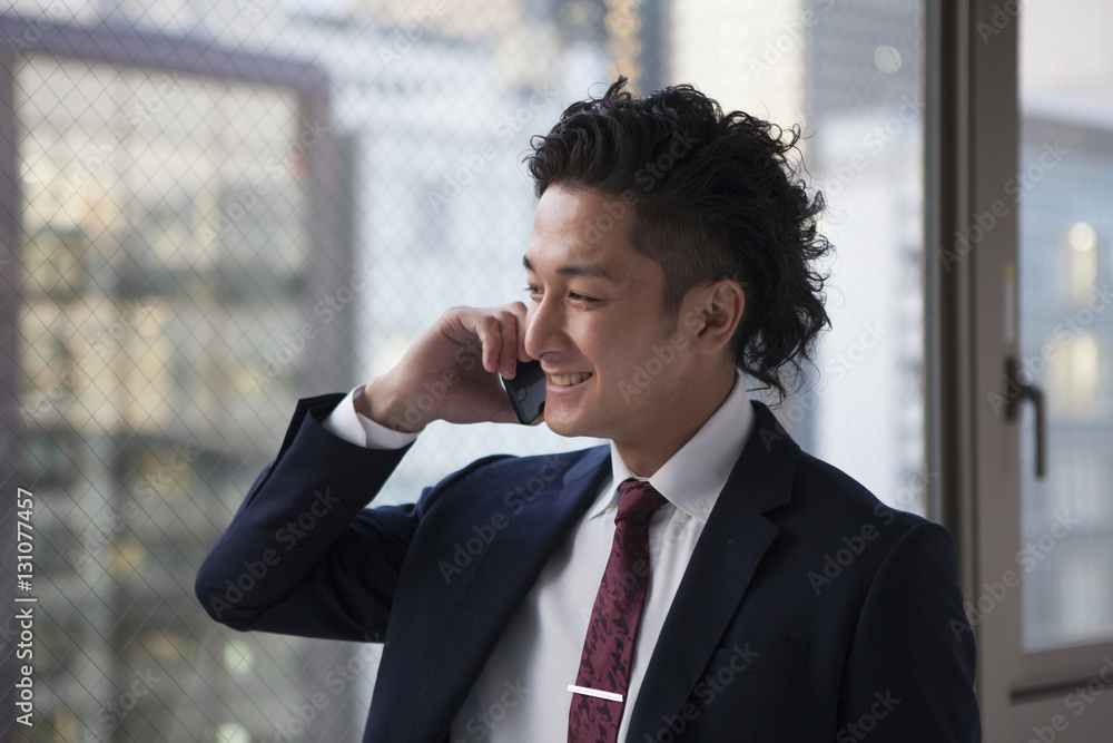 The businessman is talking on the mobile phone with a smile The businessman is talking on the mobile phone with a smile