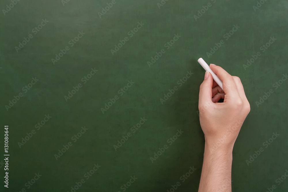 Close up of a teacher or student hand holding a chalk stick about to write  on a blank green chalkboard with copyspace Stock Photo | Adobe Stock