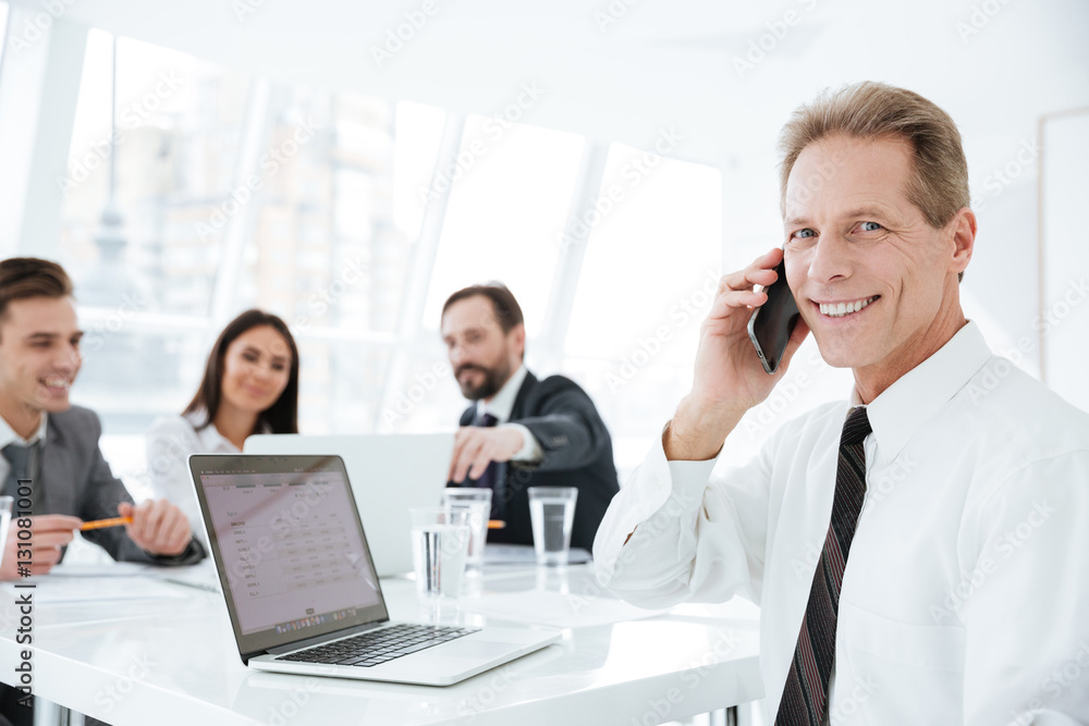 Elderly business man by the table with colleagues Elderly business man by the table with colleagues