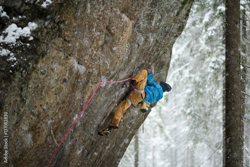Rock climber on a challenging ascent. Extreme climbing. Unique winter sports. Scandinavian nature. 