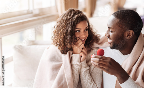 Cheerful African American couple getting engaged in the cafe