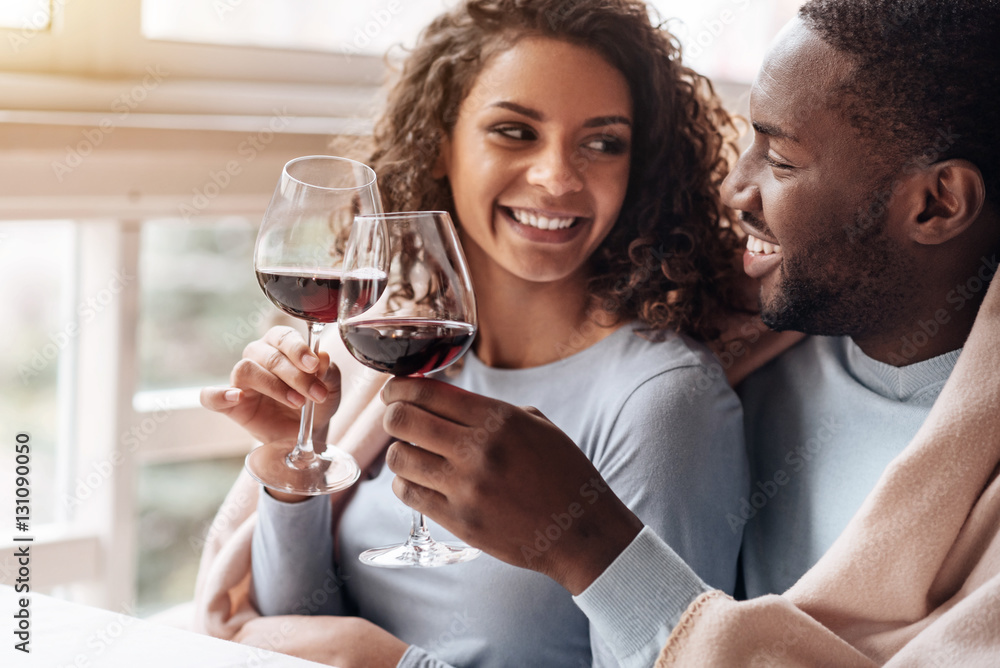 Positive African American couple holding wineglasses in the restaurant Positive African American couple holding wineglasses in the restaurant
