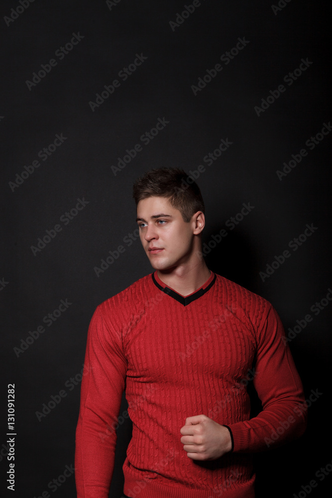 Lovely man standing on a black background. Very handsome man dressed in a red sweater. Lovely man standing on a black background. Very handsome man dressed in a red sweater.
