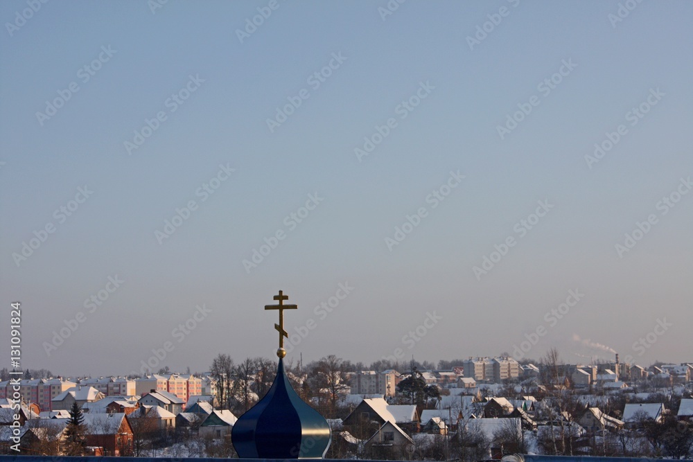 Modern architecture: orthodox church dome with cross on city houses and blue sky background
