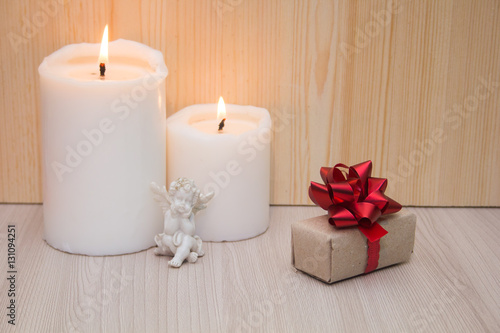 Gift boxes with red bow, white candles and a statuette of an angel. Concept for 14 February, romantic anniversary.