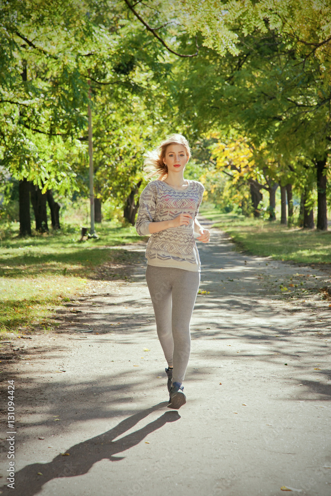 Young girl with blue eyes joging in the park. Autumn weather, yellow foliage. Young girl with blue eyes joging in the park. Autumn weather, yellow foliage.