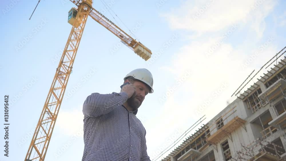 Construction manager talking by smarphone at building place.
Construction manager talking by smarphone at building place.
