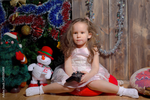 little girl in pink dress sitting by the Christmas tree decorated and waiting for when Christmas came around...