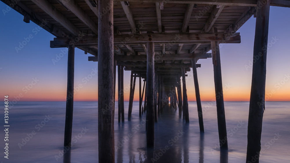 Under Nags Head Pier during a sunrise 