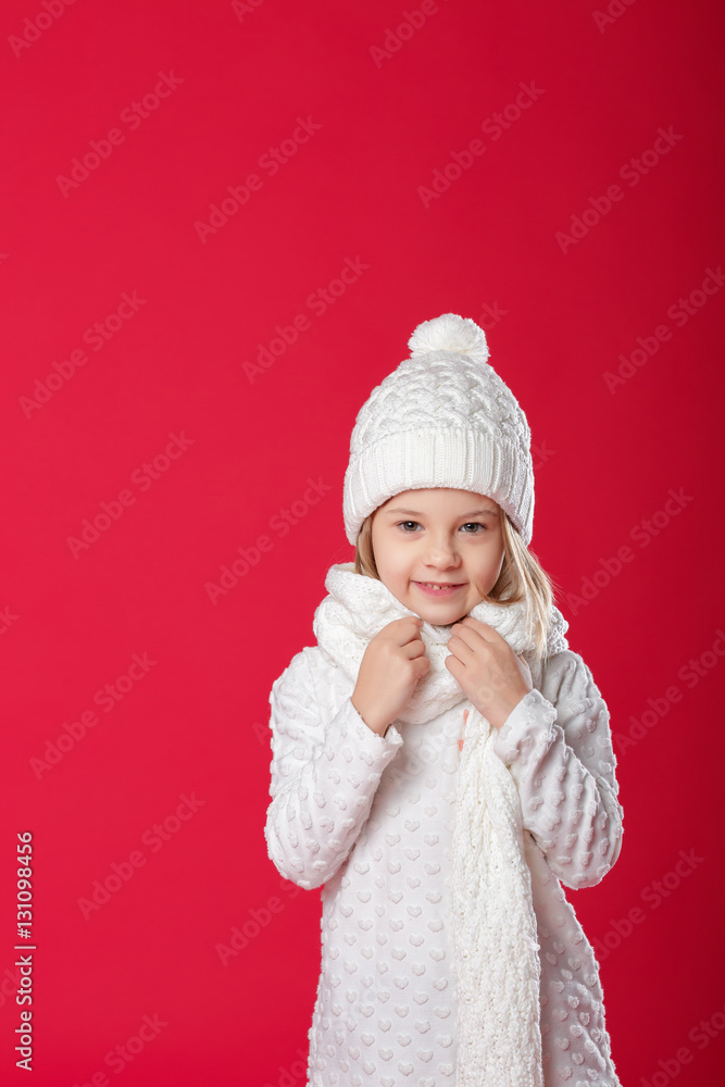 little smiling blonde girl in a white hat and scarf on red backg little smiling blonde girl in a white hat and scarf on red backg