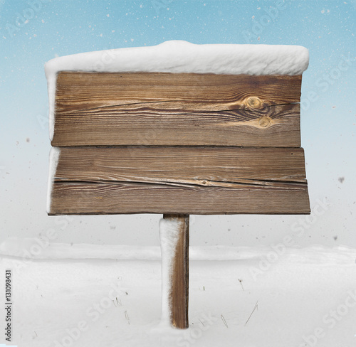 Wooden signpost with less snow on it and snowfall photo