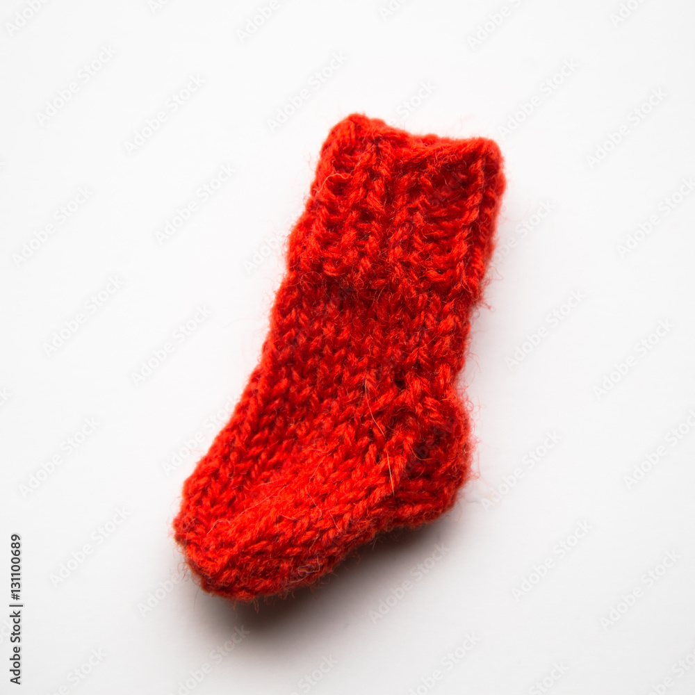 Fototapeta premium A small, hand knitted woolen sock on light background