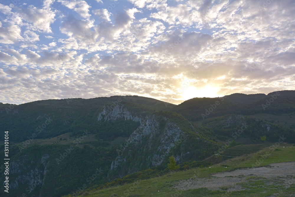 Sunset behind mountain with beautiful sunbeam through the cloud Sunset behind mountain with beautiful sunbeam through the cloud