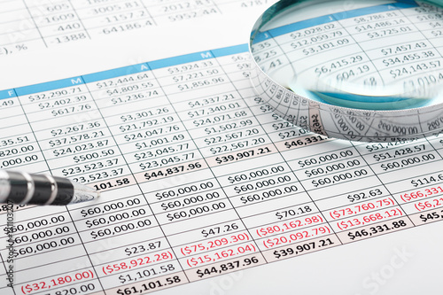 Close up of finance business sheet with pen and  magnifying glass