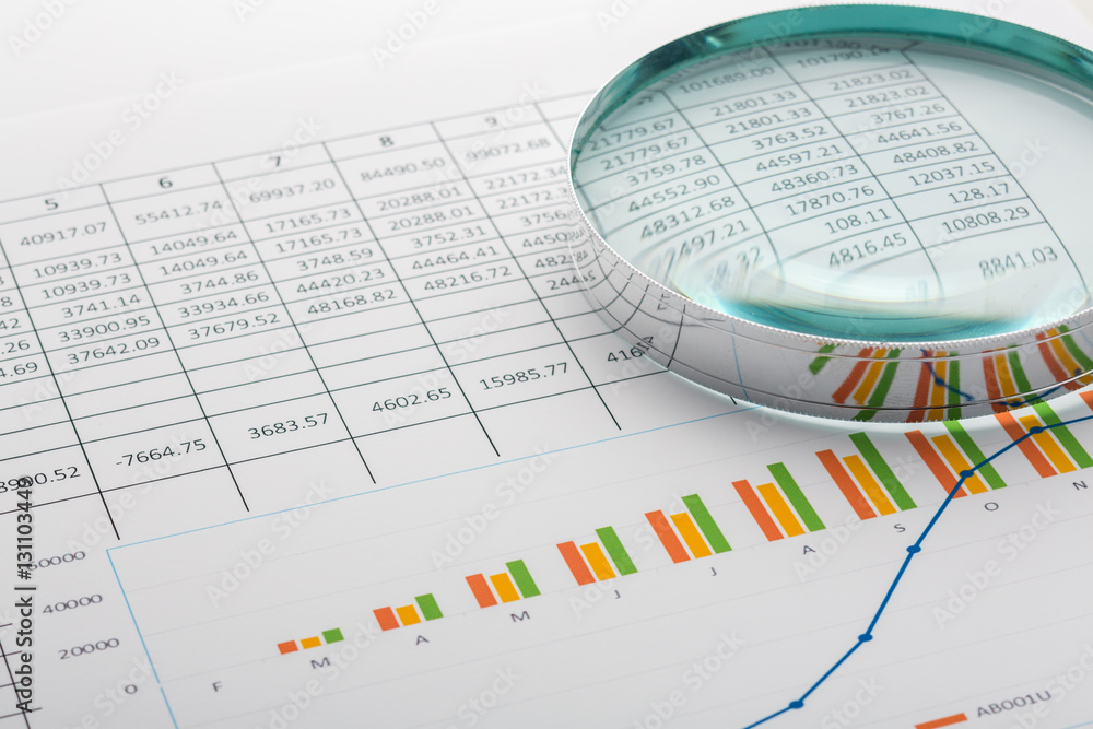 Close up of finance business sheet with magnifying glass