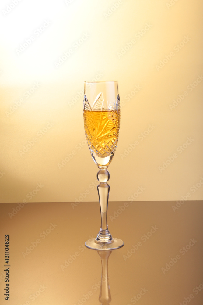 Glass of sparkling shampagne wine on a gold background