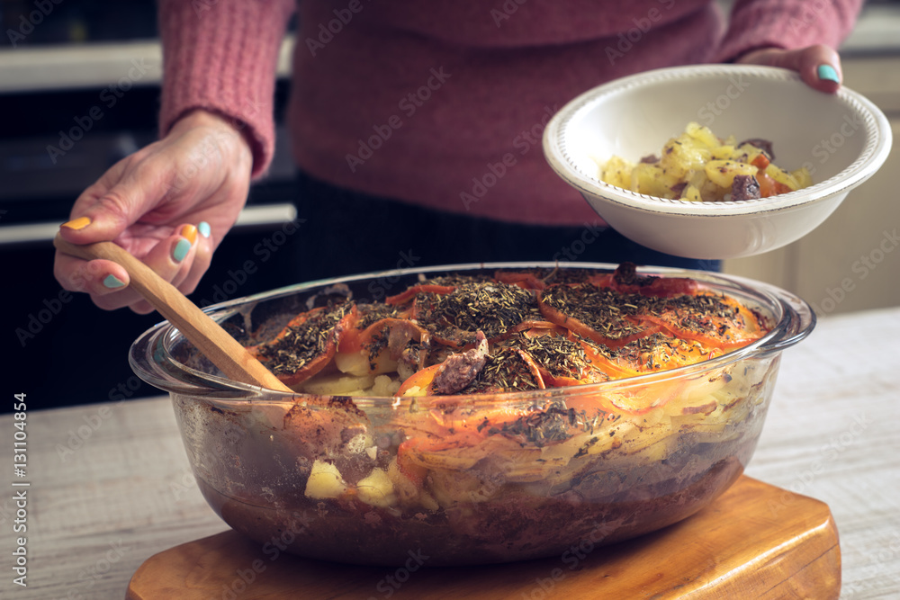 Putting baked meat with vegetables on the plate horizontal