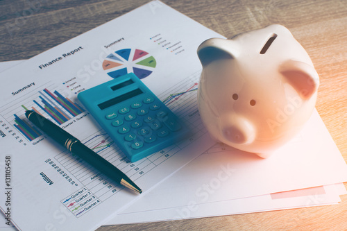 Piggy bank with calculator on wood table, business and finance concept, vintage color tone.