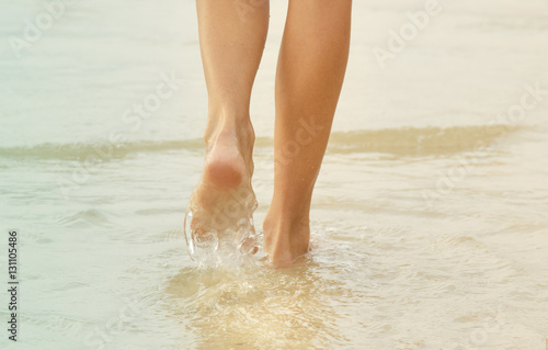 Women's feet are on the sea water.