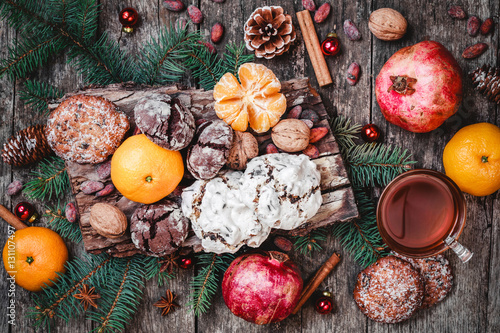 Christmas card. Cookies Chocolate, tea, pomegranate, Tangerines, Nuts, cocoa beans, Fir branches on wooden background. Xmas and Happy New Year theme. Top view, selective focus