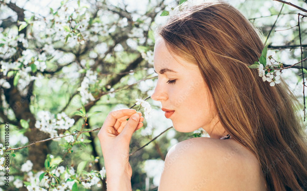 Portrait of young girl in blossom cherry garden, smelling a flower, closed eyes Portrait of young girl in blossom cherry garden, smelling a flower, closed eyes