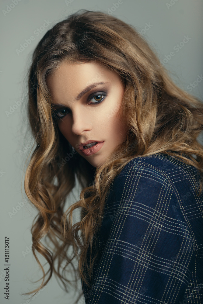 Fashion studio portrait of a beautiful young girl with an evening make-up and hairstyle on a gray background Fashion studio portrait of a beautiful young girl with an evening make-up and hairstyle on a gray background