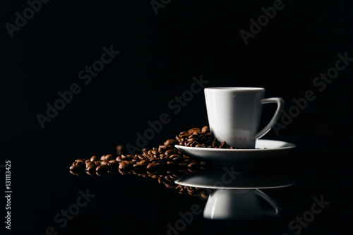 Small cup of black coffee on a dark background with coffee beans