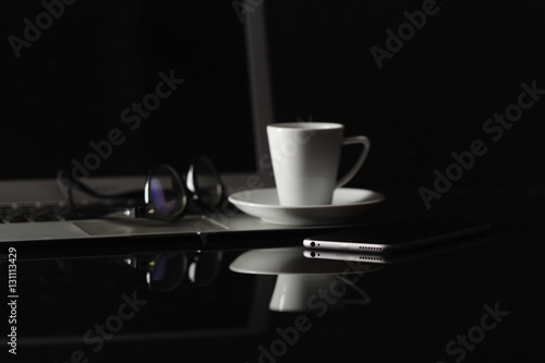 cup of coffee and smart phone over dark background
