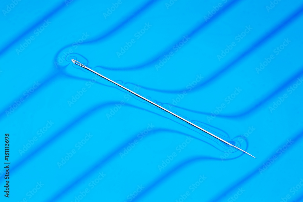 Physical experiment needle floats on water surface. Stock Photo