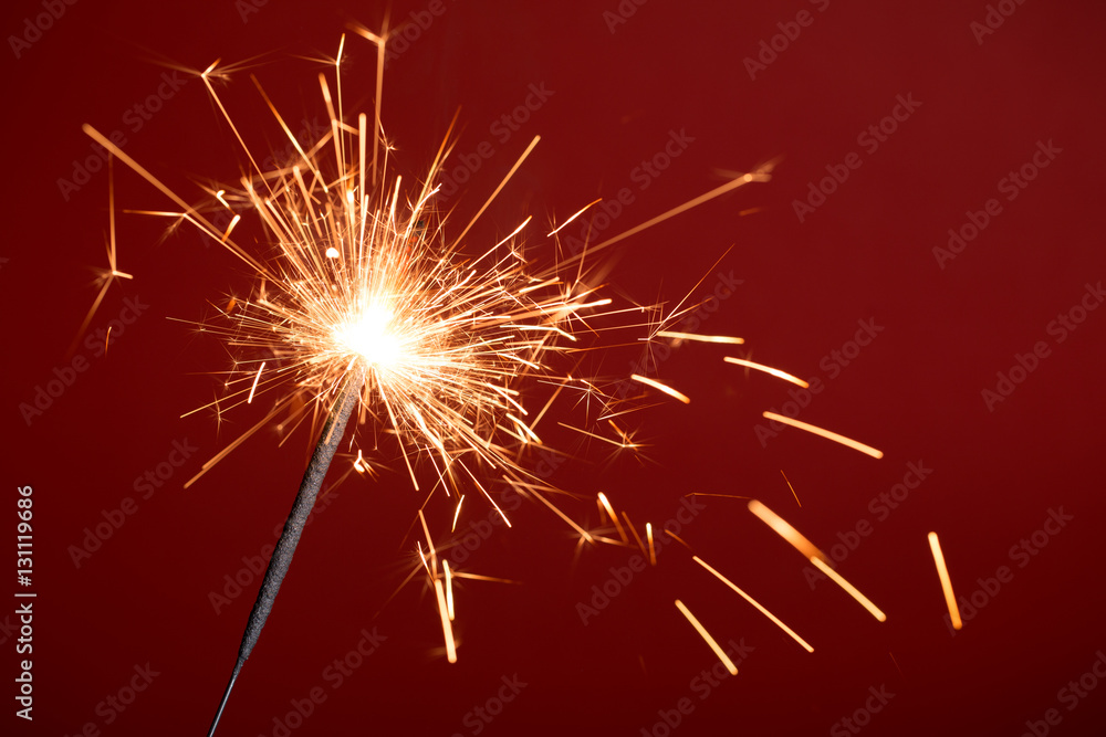 Fototapeta premium Burning sparkler on red background