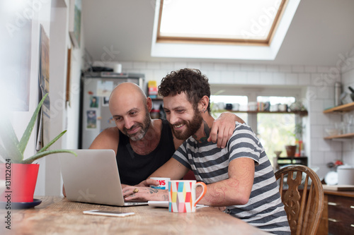 Gay couple using laptop in the kitchen