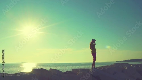 girl standing near the ocean against the sun