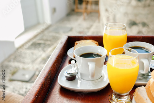 Orange juice and coffee as a part of a continental breakfast served on a wooden tray