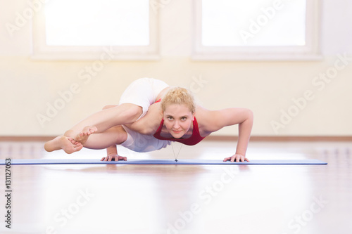 Young woman in white doing yoga pose arm balance photo