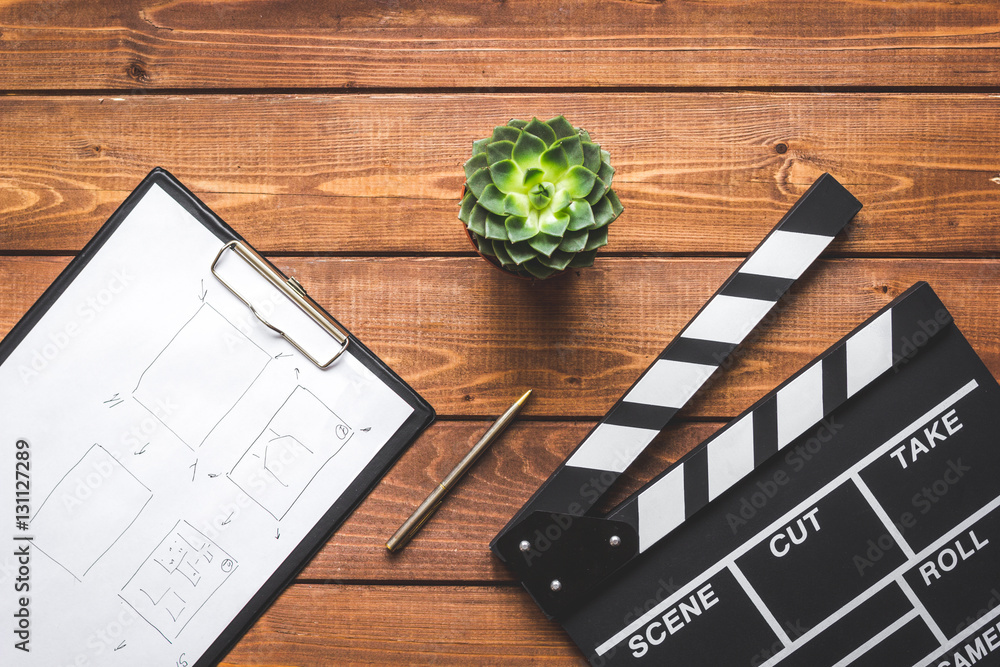 Fototapeta premium Screenwriter desktop with movie clapper board wooden background top view