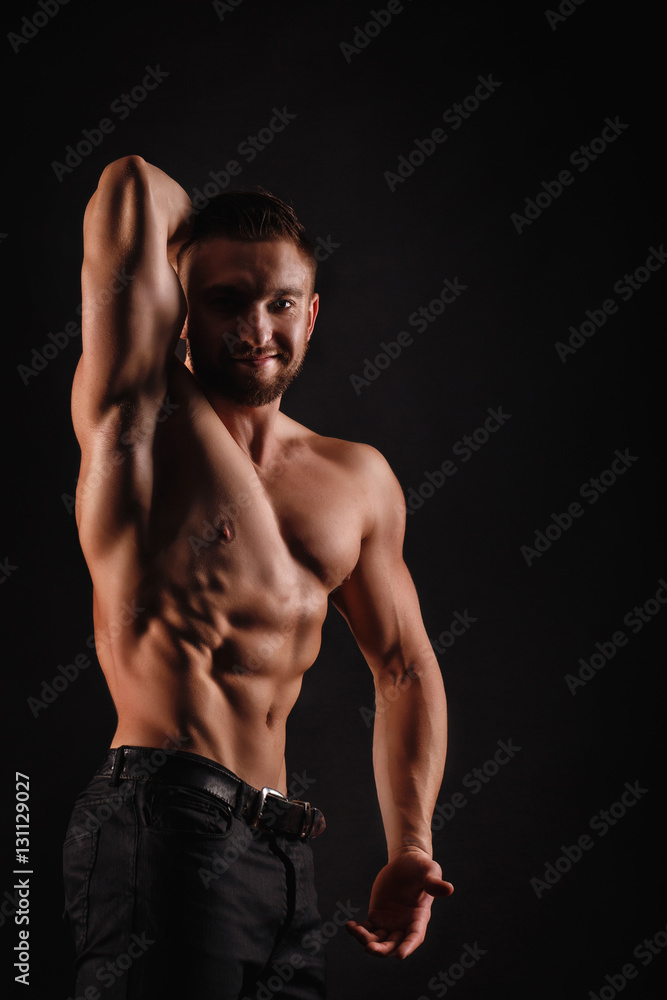 Bodybuilder posing on a black background. Dramatic portrait of an athlete. Drying. Relief and sculptural muscles of the body. Healthy lifestyle concept. Abdominal muscles and shoulders, triceps. Bodybuilder posing on a black background. Dramatic portrait of an athlete. Drying. Relief and sculptural muscles of the body. Healthy lifestyle concept. Abdominal muscles and shoulders, triceps.