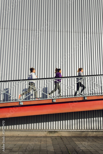 Group of three women running on a ramp. Urban outdoor training people.