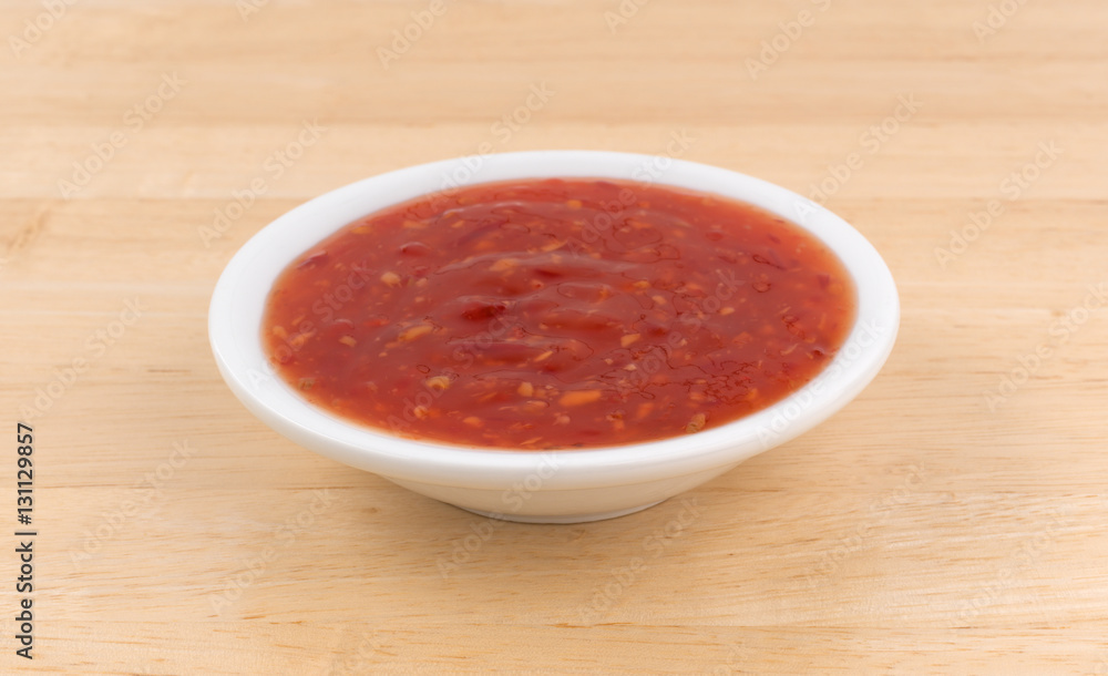 Chili chicken sauce portion in a small bowl atop a wood table. Chili chicken sauce portion in a small bowl atop a wood table.