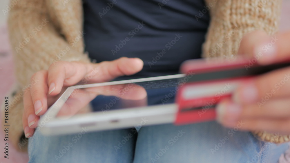 Young woman buying goods from the internet and entering number security code from credit card on digital tablet. Online, technology and internet concept