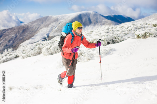 Girl with backpack walking on snow in the mountains.