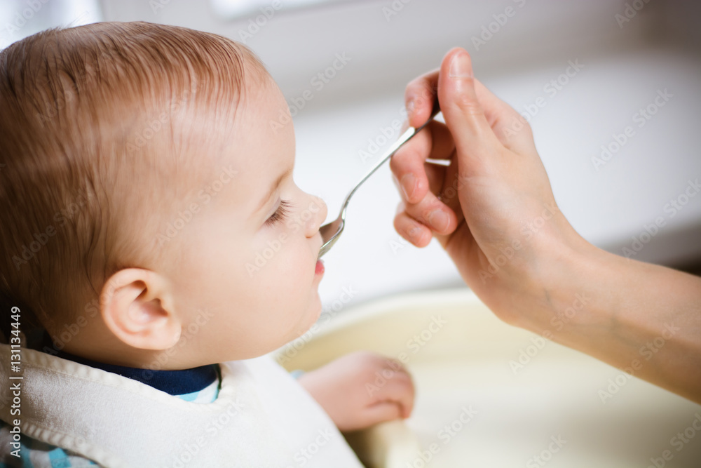 Mother gives baby food from a spoon Mother gives baby food from a spoon