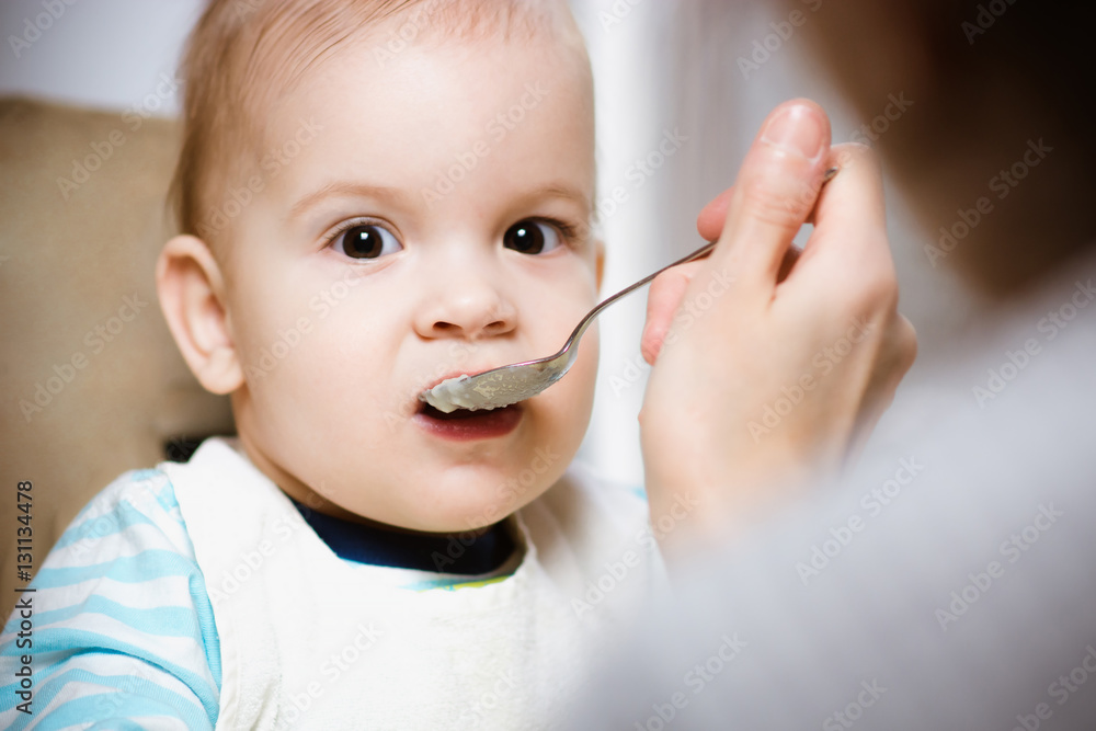 Mother gives baby food from a spoon Mother gives baby food from a spoon