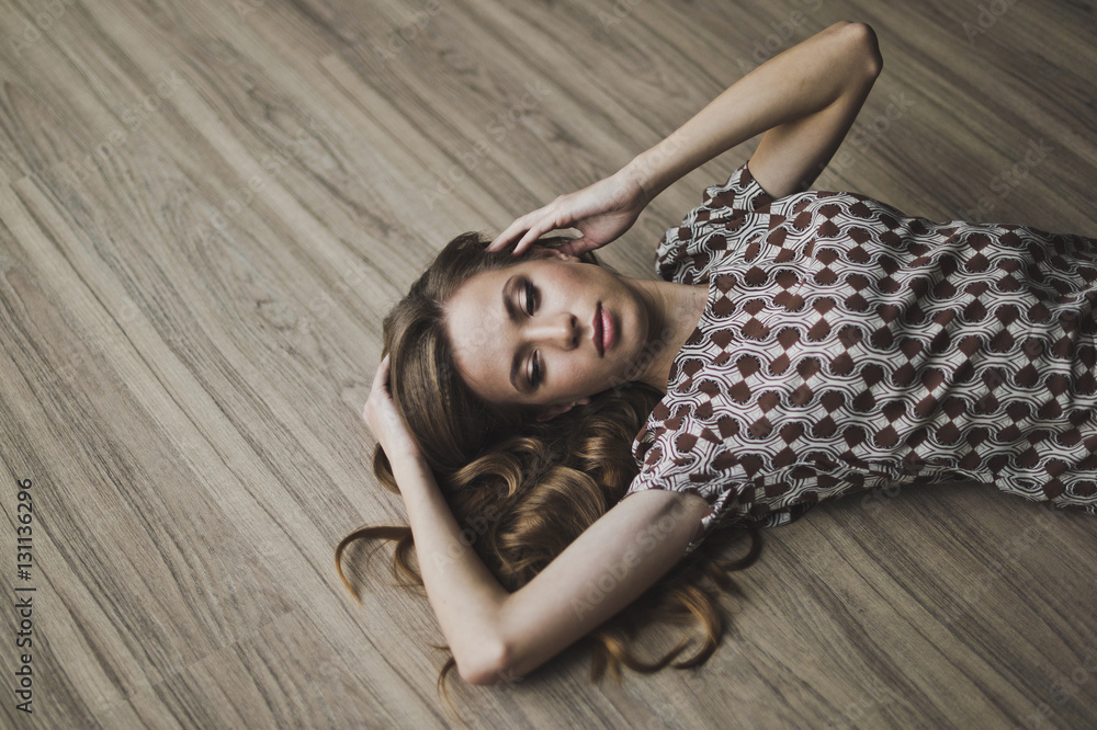 The girl lay on the parquet floor, arms outstretched 6963. - obrazy, fototapety, plakaty 