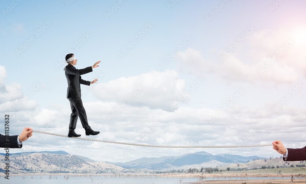 Business concept of risk support and assistance with man balancing on rope Business concept of risk support and assistance with man balancing on rope