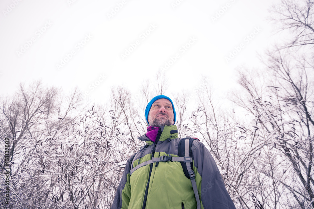 Smiling hiker is relaxing in the winter forest