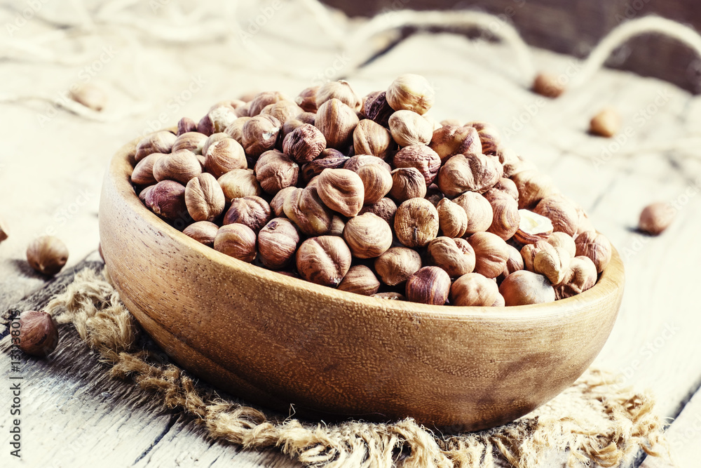 Peeled hazelnuts in a bowl, rustic style, dark wooden background Peeled hazelnuts in a bowl, rustic style, dark wooden background