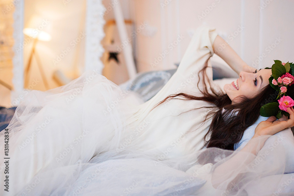 Girl with a wreath on his head on the bed smiling Girl with a wreath on his head on the bed smiling