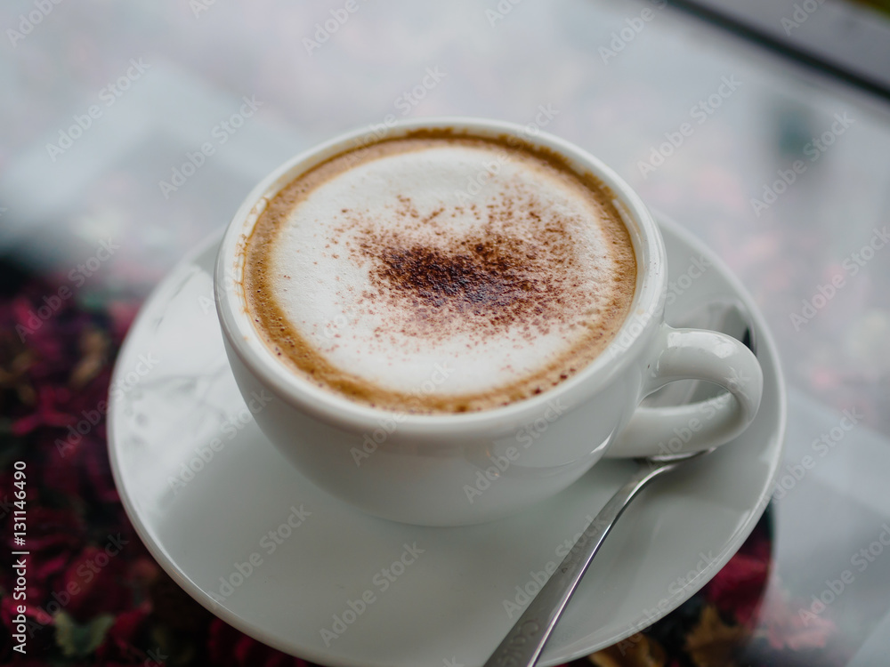 Top view of cappuccino coffee on white cut and on glass table with blur background Top view of cappuccino coffee on white cut and on glass table with blur background